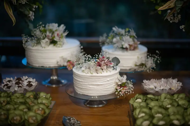 Hvite bryllupskaker med blomster på pyntet kakebord